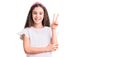 Cute hispanic child girl wearing casual white tshirt smiling with happy face winking at the camera doing victory sign with fingers Royalty Free Stock Photo