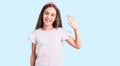 Cute hispanic child girl wearing casual white tshirt waiving saying hello happy and smiling, friendly welcome gesture Royalty Free Stock Photo