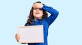 Cute hispanic child with long hair holding empty white chalkboard stressed and frustrated with hand on head, surprised and angry Royalty Free Stock Photo