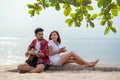 Cute hispanic couple playing guitar serenading on beach in love and embrace, happy and relax outdoor on the sand. Royalty Free Stock Photo
