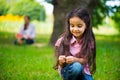 Cute hispanic girl in park with mother on background