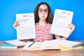 Cute hispanic girl showing failed and passe exam sitting on the table puffing cheeks with funny face Royalty Free Stock Photo