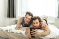 Cute homosexual couple taking selfie on bed
