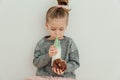 Cute hungry little girl with chocolate donut and bottle of milk. White background, studio shot