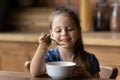 Cute hungry little girl enjoying eating cereal for morning breakfast Royalty Free Stock Photo