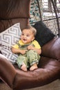 cute infant facial expressing sitting at swing from flat angle indoor shot