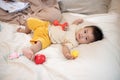 A cute, innocent Asian baby boy is playing with toys while lying on the bed in the bedroom Royalty Free Stock Photo