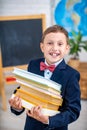 Cute inquisitive little schoolboy wears school textbooks. Back to school