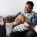 Cute interracial couple on a couch sharing smartphone love, internet and music concept Royalty Free Stock Photo