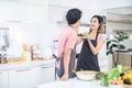 Cute joyful couple asian cooking together and adding spice to meal, laughing and spending time together in the kitchen Royalty Free Stock Photo