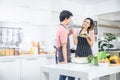 Cute joyful couple asian cooking together and adding spice to meal, laughing and spending time together in the kitchen Royalty Free Stock Photo