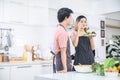 Cute joyful couple asian cooking together and adding spice to meal, laughing and spending time together in the kitchen Royalty Free Stock Photo