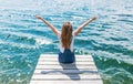 Cute joyfull teenage girl sitting on small dock and looking at the river. Royalty Free Stock Photo