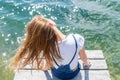 Cute joyfull teenage girl sitting on small dock and looking at the river. Royalty Free Stock Photo