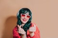 Cute kawaii girl with green hair and headphones, red lips, sunglasses showing korean hearts with fingers and smiling