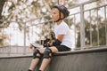 Cute kid boy child in a helmet sitting in a special area in skatepark and holding skateboard. Summer sport activity concept. Happy Royalty Free Stock Photo