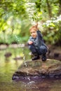 Cute kid boy near water splashing. Caucasian White toddler playing in forest stream Royalty Free Stock Photo