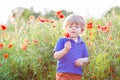 Cute kid boy with poppy flower on poppy field on warm summer day Royalty Free Stock Photo