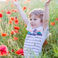 Cute kid boy with poppy flower on poppy field on warm summer day Royalty Free Stock Photo