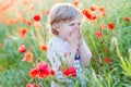 Cute kid boy with poppy flower on poppy field on warm summer day Royalty Free Stock Photo