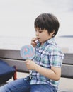 Cute kid eating lollipop, Happy little boy holding big sugar candy, Child with smiling face eat sweets, Active childhood enjoying Royalty Free Stock Photo