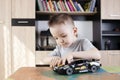 Cute kid focused on assembling toy car at his playing table