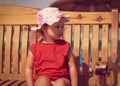 Cute kid girl in hat sitting on the bench on the beach