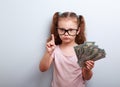 Cute kid girl holding dollars and have an idea how earning much Royalty Free Stock Photo