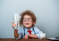 Cute kid girl holding dollars and have an idea how earning much money in crisis. Serious child teaching in eyeglasses Royalty Free Stock Photo