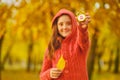 Cute kid girl holds a alarm clock in the Autumn park. Royalty Free Stock Photo