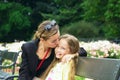 Cute kid girl hugging her mother on a summer meadow on beautiful