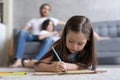 Cute kid girl playing on floor, preschool little girl drawing with colored pencils on paper spending time with family