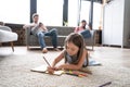 Cute kid girl playing on floor, preschool little girl drawing with colored pencils on paper spending time with family