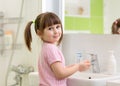 Cute kid girl with ponytail in pink bathrobe washing her hands. Royalty Free Stock Photo