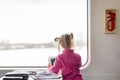 Cute kid girl travelling by railroad. Child smiling and sitting in train. Baby looking in wide bright sunny window .Back view. Cop Royalty Free Stock Photo