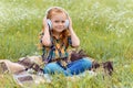 cute kid listening music in headphone while sitting on blanket in field Royalty Free Stock Photo