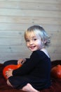 Kid little girl sitting bed with pumpkins. Halloween celebration Royalty Free Stock Photo