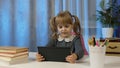 Cute kid pupil watching video lesson, studying using digital tablet computer, doing homework online Royalty Free Stock Photo