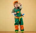 Cute kid repairman in protective helmet with toolbelt of toy tools for building. Happy child boy in uniform and hard hat Royalty Free Stock Photo