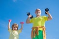 Cute kid and senior man exercising with dumbbells. Happy little boy and grandfather lifting dumbbells on blue sky Royalty Free Stock Photo