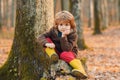 Cute kid sitting on fallen leaves. Autumn dream. Kid dreams on autumn nature. Childhood dream concept. Daydreamer child