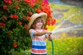 Cute Kid in straw hat is laughing with water spraying hose Royalty Free Stock Photo