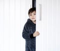 Cute kid wearing fluffy pajamas standing behind wardrobe, little boy looking at camera with smiling face while holding the white Royalty Free Stock Photo