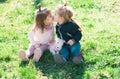 Cute kids love. Little girl kissing little boy outdoors in park. Children in beautiful spring green field. Royalty Free Stock Photo