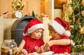 Cute kids in santa hats preparation holiday dinner for family. Santa cook. Cookie on Christmas Eve as a thank Santa gift