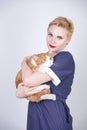 Cute kind woman with short hair in pinup polka dot dress holding her beloved pet on a white background in the Studio. plus size ad Royalty Free Stock Photo