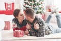 Cute kiss. Lovely young couple lying on the floor of living room at new year time with gift boxes