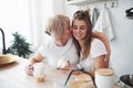 Cute kiss. Mother and daughter having good time in the kitchen