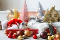 Cute kitten sleeping on cozy santa hat with red and gold ornaments with warm festive lights