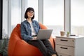 Cute female worker with portable laptop looking at window